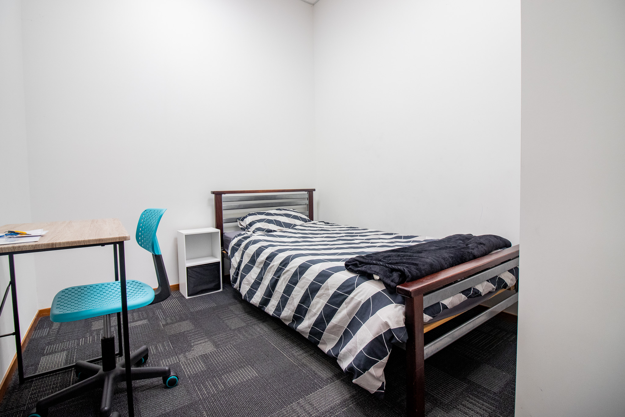 Photo of single skylight bedroom with bed made up and desk with blue chair